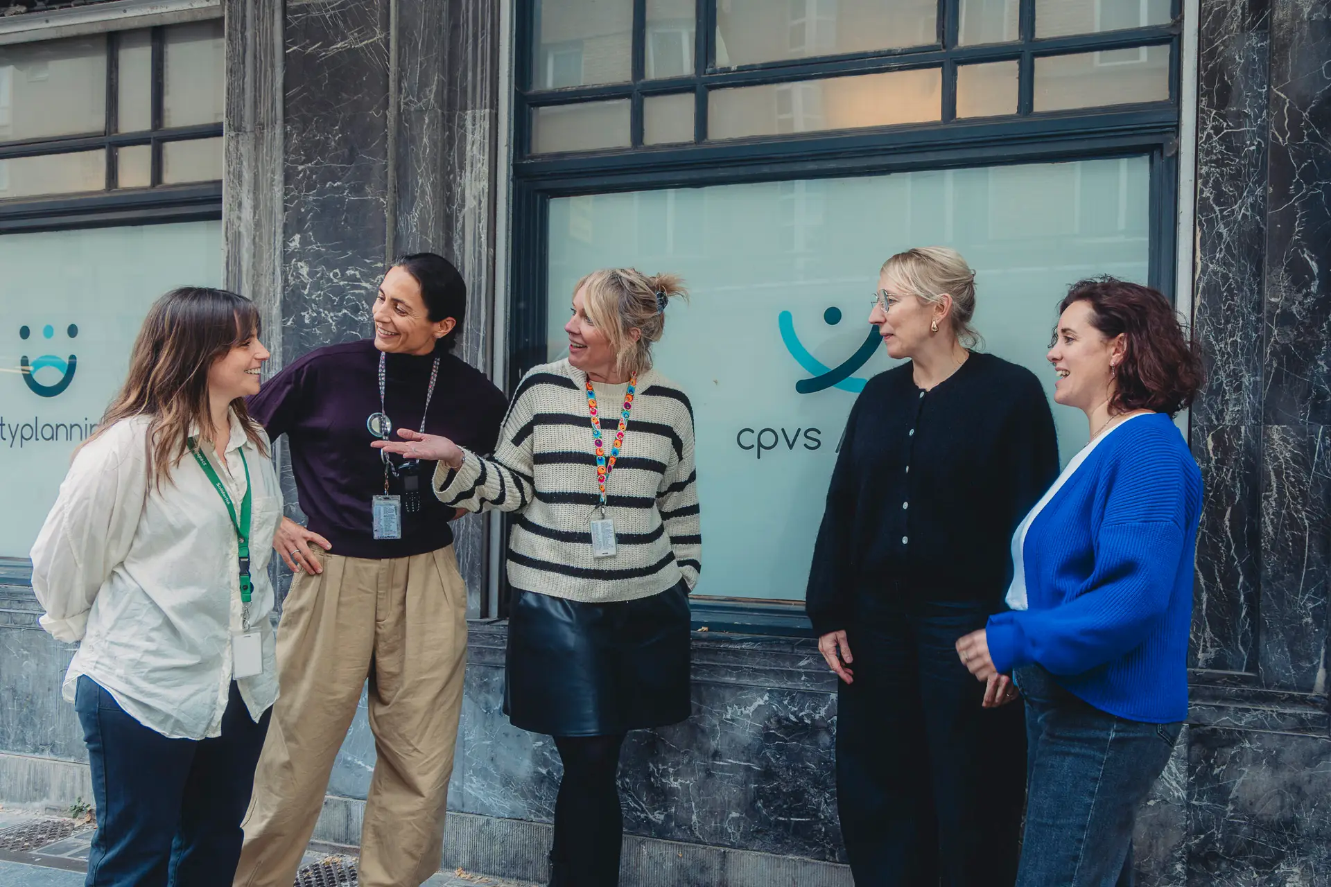 Cinq membres de l'équipe échangent en souriant devant les locaux du CPVS