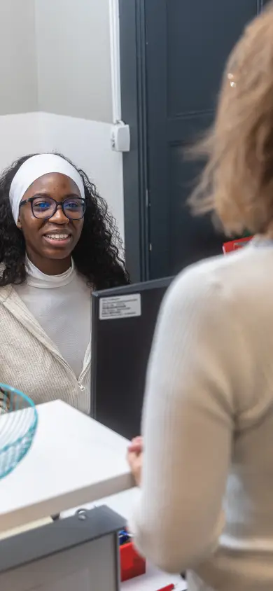 Une professionnelle accueille une visiteuse à un bureau d'accueil